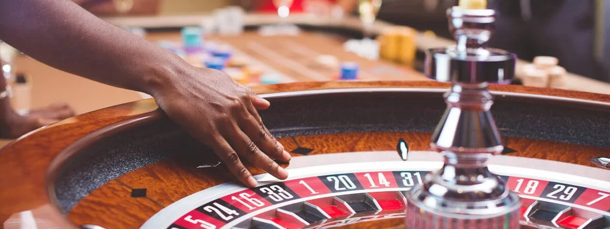 Professional croupier in an elegant gaming studio surrounded by roulette wheels and soft ambient lighting — premium live dealer standard at CrownBD for Bangladeshi members